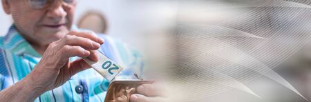 Old woman taking out a banknote from her wallet; panoramic banner