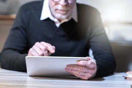 Senior man using his tablet at home