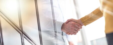 Businesswoman and businessman shaking hands in office; multiple exposure
