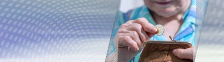 Old woman taking out a coin from her wallet; panoramic bannerの写真素材