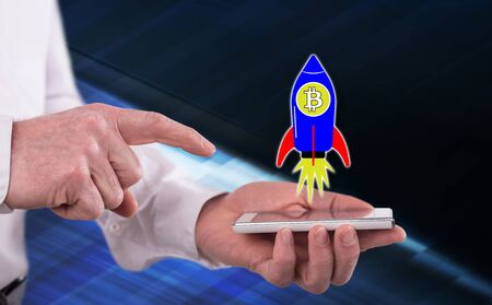 Bitcoin rise concept above a smartphone held by a manの写真素材