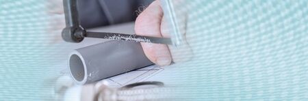 Plumber sawing a pvc pipe, closeup; panoramic banner