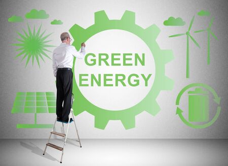 Man on a ladder drawing green energy concept on a wallの写真素材