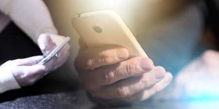 Hand holding a phone, closeup, hard light effect; multiple exposure