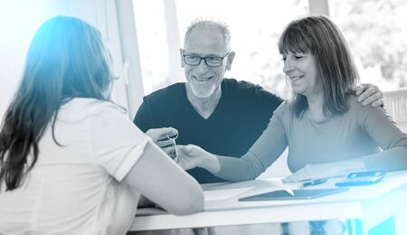 Real estate agent giving house keys to senior couple; light effectの写真素材
