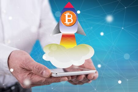 Bitcoin rise concept above a smartphone held by handsの写真素材