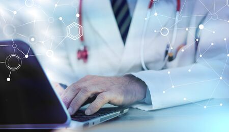 Male doctor using laptop in medical office; light effectの写真素材