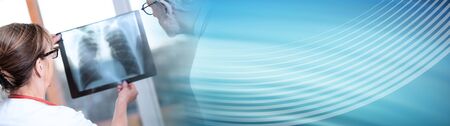 Two doctors examining x-ray report in medical office; panoramic banner