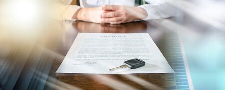 Female car buyer sitting in front of contract and car key; multiple exposureの写真素材