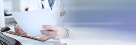 Doctor reading medical notes at his office; panoramic bannerの写真素材