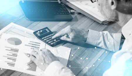Accountant working on financial documents and using a calculator; light effect