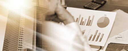 Businessman analyzing financial paperwork; multiple exposure