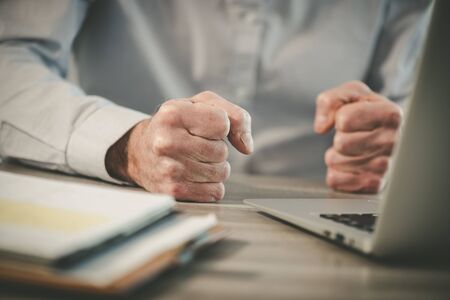 Enraged businessman banging his clenched fists on the deskの写真素材