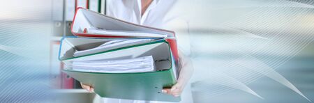 Businesswoman holding binders at office; panoramic banner