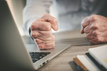 Enraged businessman banging his clenched fists on the deskの写真素材
