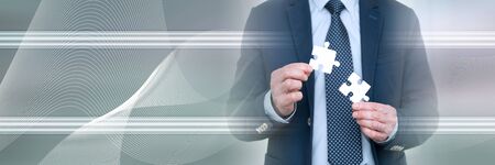 Businessman joining two puzzle pieces, teamwork concept; panoramic bannerの写真素材