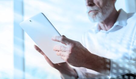Senior businessman using a digital tablet in office; light effect