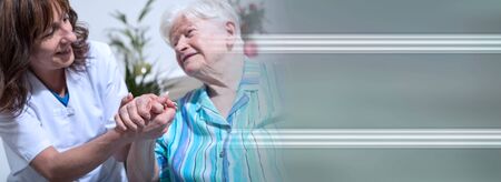 Nurse holding the hand of an old woman; panoramic bannerの写真素材
