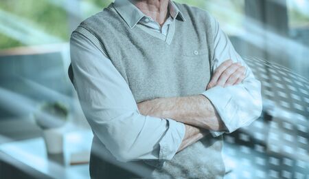 Businessman with arms crossed standing in office; light effectの写真素材