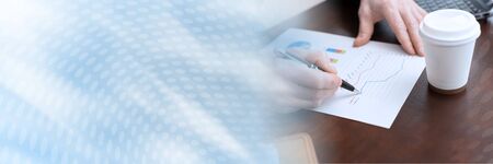Businessman analysing marketing graphs at office; panoramic banner