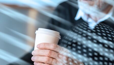 Businessman holding a paper coffee cup during break; light effectの写真素材