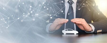 Insurer protecting a car with his hands; panoramic bannerの写真素材