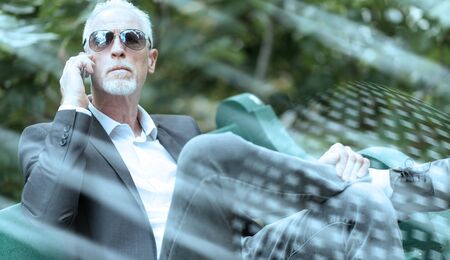Mature man talking on mobile phone outdoors; light effectの写真素材