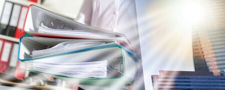 Businesswoman holding binders at office; multiple exposureの写真素材