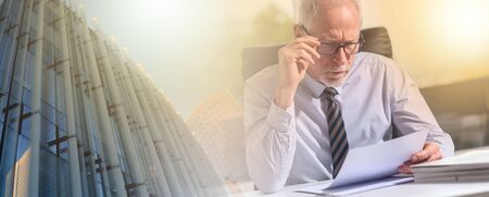 Portrait of mature businessman checking a document in office; multiple exposure; panoramic bannerの写真素材