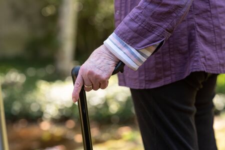 Elderly woman holding a walking stick, outdoorsの写真素材