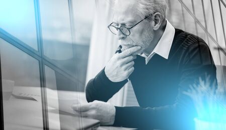 Senior businessÃ£Â¹an working on document at office; multiple exposureの写真素材