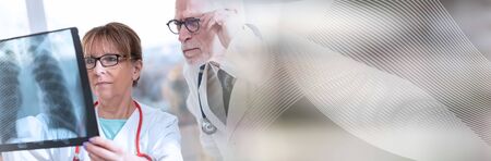 Two doctors examining x-ray report in medical office; panoramic bannerの写真素材