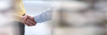 Businesswoman and businessman shaking hands in office; panoramic bannerの写真素材