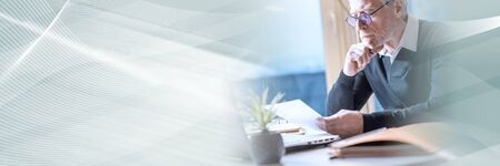 Senior businessman reading a document at office; panoramic bannerの写真素材