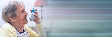 Elderly woman using an asthma inhaler; panoramic bannerの写真素材