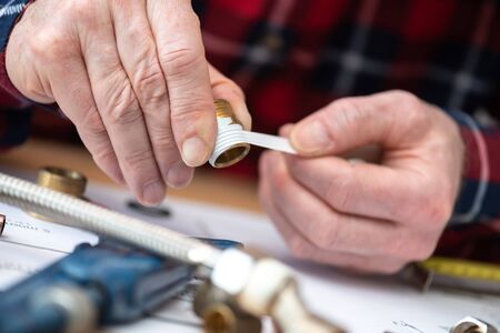 Plumber putting seal tape on a thread of a plumbing fittingの写真素材