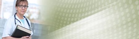 Portrait of female doctor standing and holding a medical textbook; panoramic bannerの写真素材