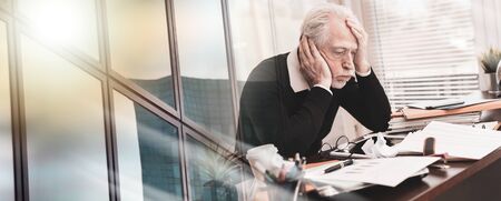 Overworked businessman sitting at a messy desk in office; multiple exposureの写真素材