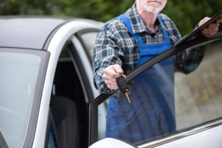 Car mechanic delivering car keys after car engine checkingの写真素材