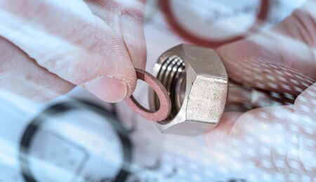 Plumber putting a gasket on a plumbing fitting, closeup; light effectの写真素材