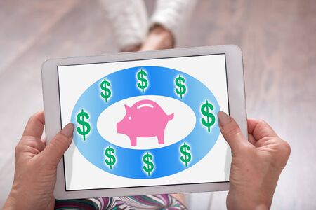 Saving money concept shown on a tablet held by a womanの写真素材