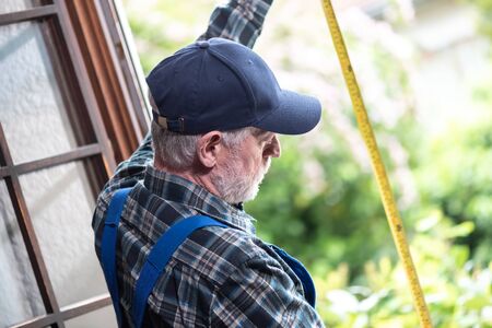 Senior repairman taking measures with tape measureの写真素材