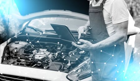 Car mechanic using laptop for checking car engine; light effectの写真素材