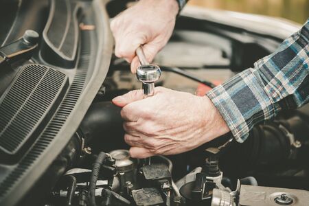 Hands of car mechanic repairing a car engine