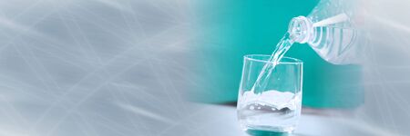 Pouring water from a bottle into a glass; panoramic banner