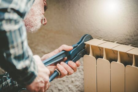 Repairman working on radiator with wrenchの写真素材