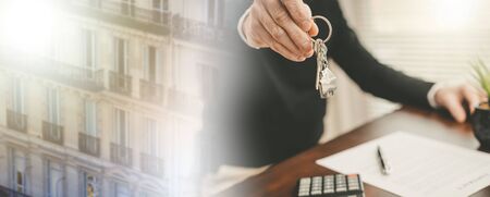 Real estate agent showing house keys after contract signing; panoramic banner; multiple exposureの写真素材