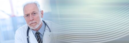 Portrait of male senior doctor looking the camera; panoramic bannerの写真素材
