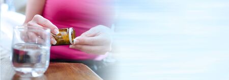 Sick woman sitting and taking drugs; panoramic bannerの写真素材