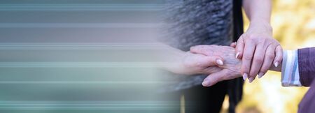 Concept of elderly support; young and aged holding hands; panoramic bannerの写真素材